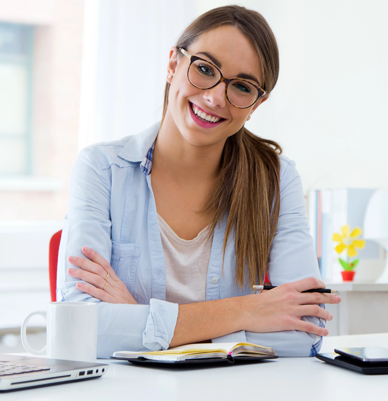 Smiling woman with glasses at a desk.